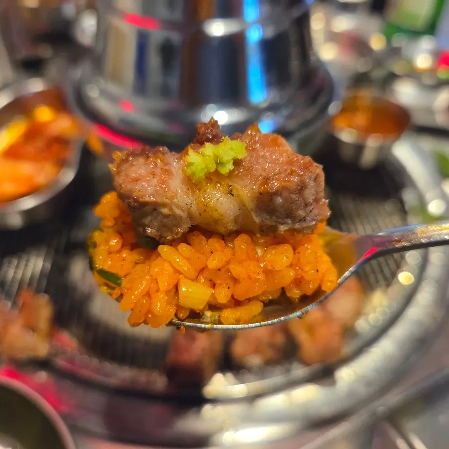 A piece of meat placed on top of the kimchi fried rice