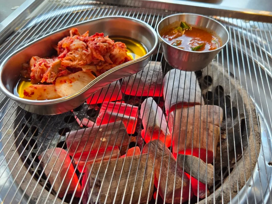 Charcoal placed on the grill along with kimchi and fermented anchovy sauce