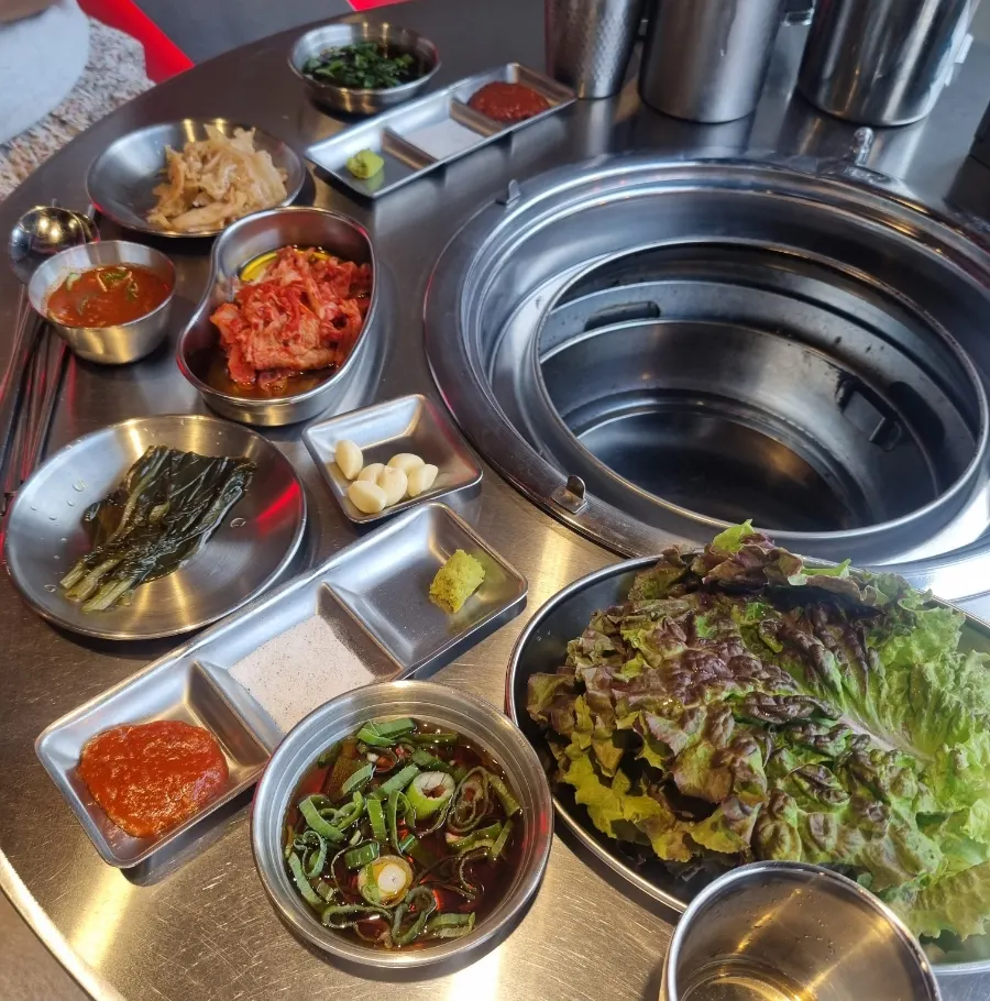 Banchan spread of wild garlic leaves, aged kimchi, lettuce, and sauces