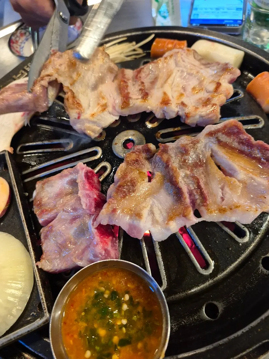 Raw ribs and vegetables grilling on the cast-iron pan