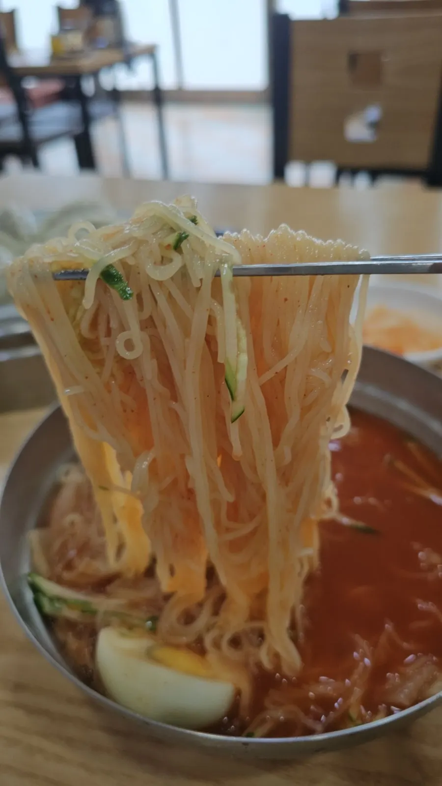 Chewy milmyeon noodles lifted up with chopsticks
