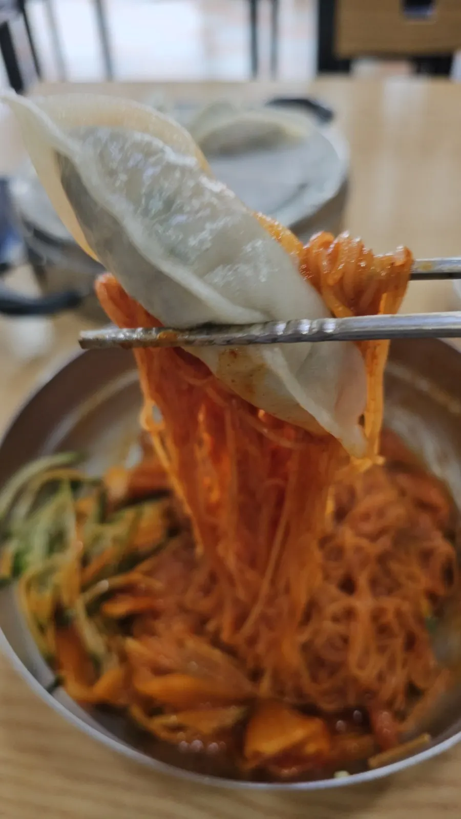 Lifting up a bite of bibim milmyeon noodles