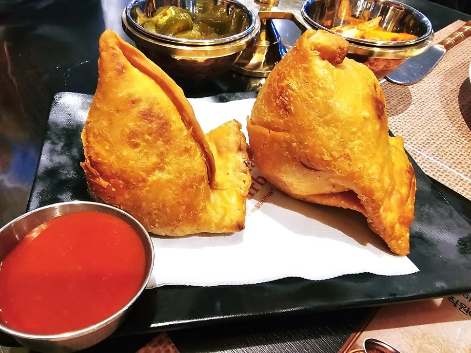 A plate with a large samosa at India The Durbar Samseong Station Branch