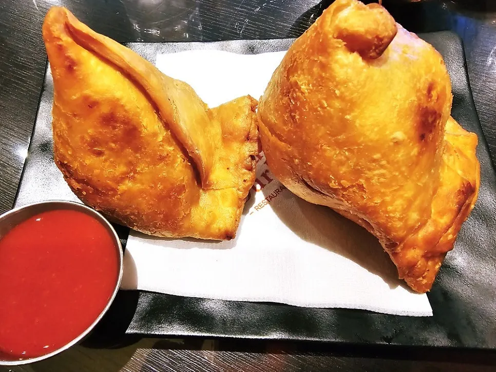 A large golden, crispy fried samosa