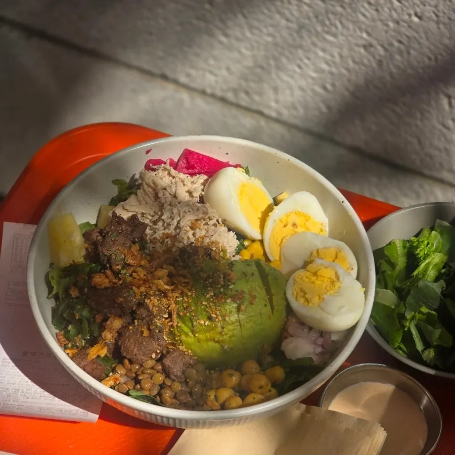 A poke bowl filled with avocado, egg, chicken breast and steak