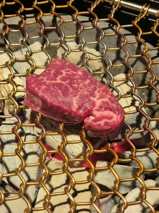 Thick hanwoo tenderloin grilling over charcoal