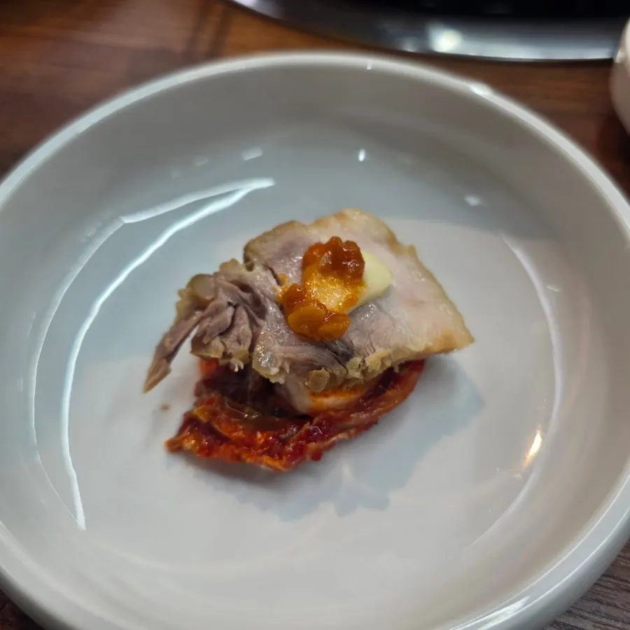 A piece of bossam topped with kimchi