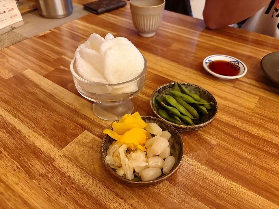Complimentary rakkyo, pickled radish, edamame, and shrimp chips