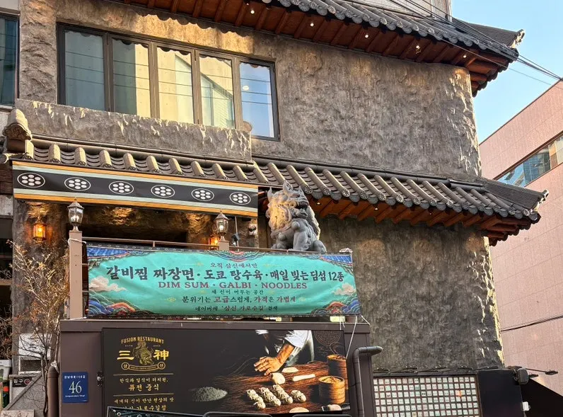 Samsin's entrance with a stone statue atop the stairs beside the building