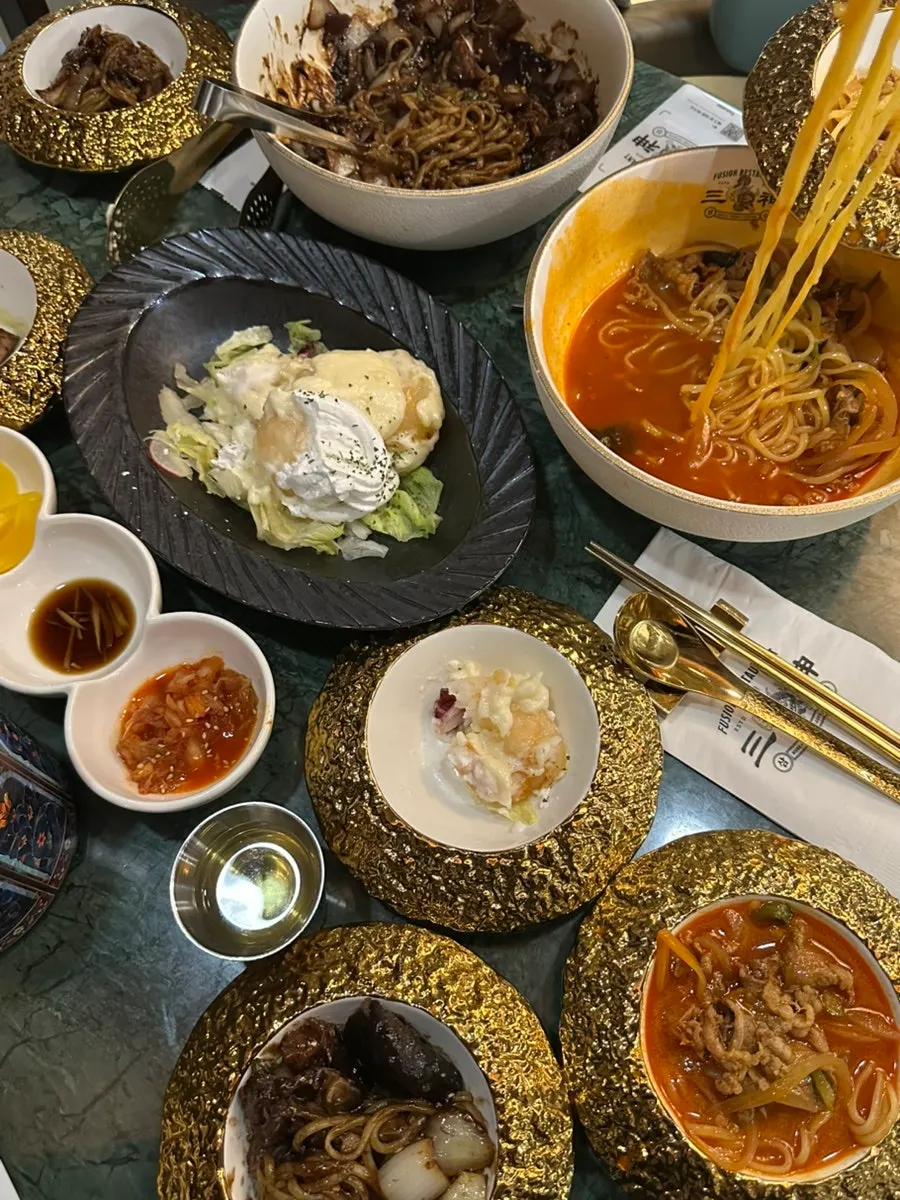 짙은 초록 테이블에 놓인 금색 접시와 수저