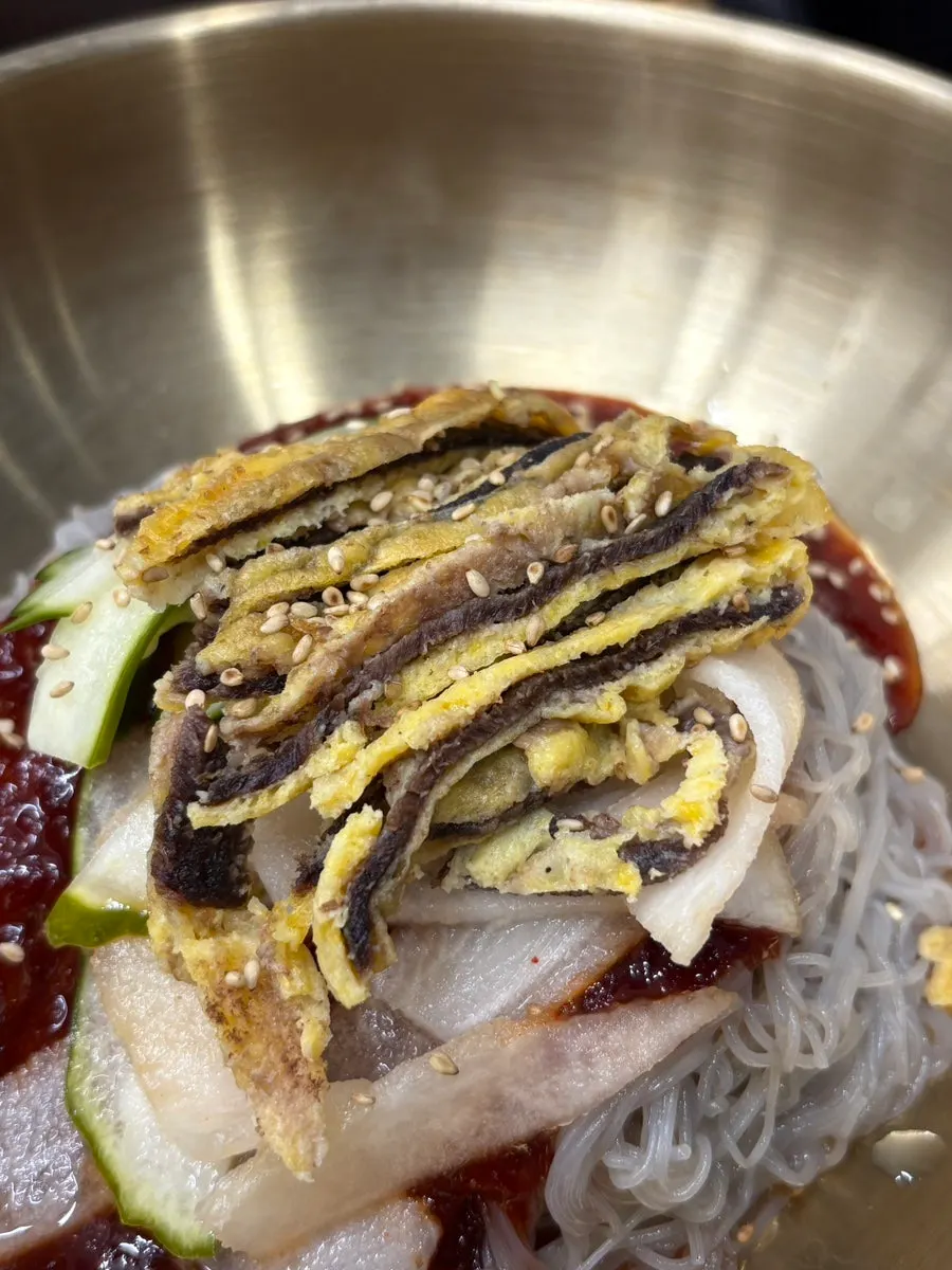 A spoonful of rice topped with meat and kimchi