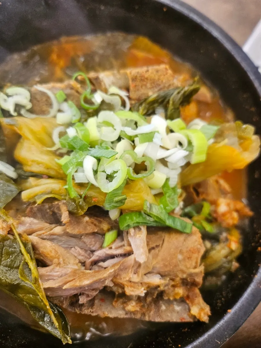 Stone pot gamjatang topped with green onion and napa cabbage