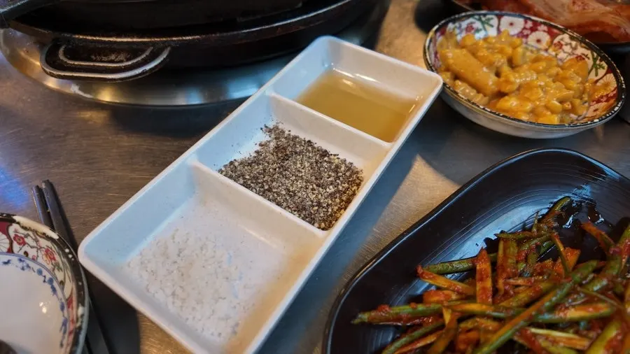 Side dishes set out: scallion salad, aged kimchi, lettuce wraps