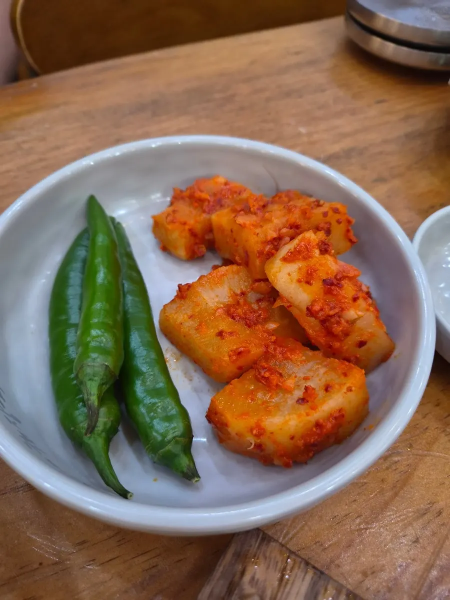 Basic side dishes of radish kimchi, chili peppers, and lettuce