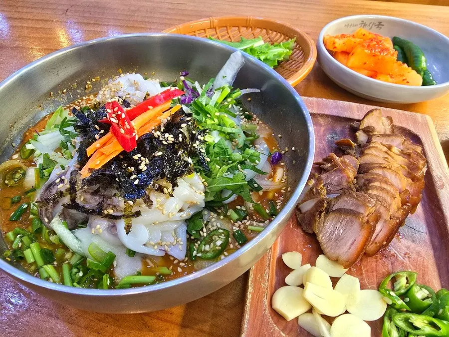 A bite of dombe gogi topped with mulhoe vegetables and squid