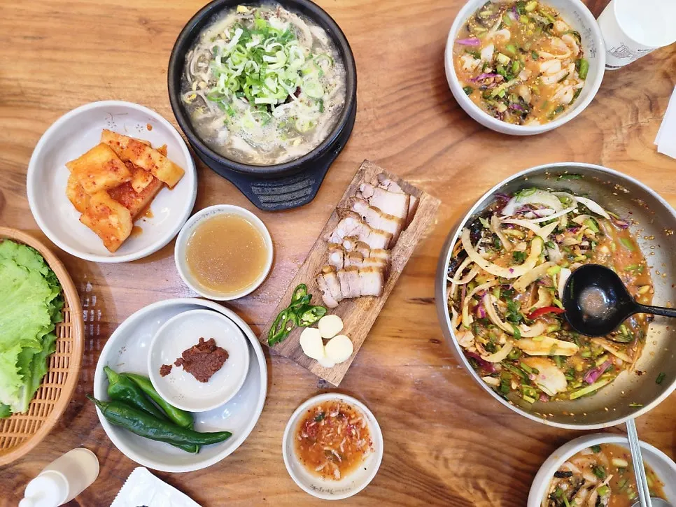 Table spread of tripe soup, hanchi mulhoe, and dombe pork