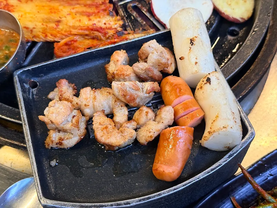 Grill with kimchi, rice cake, and sausage cooking alongside