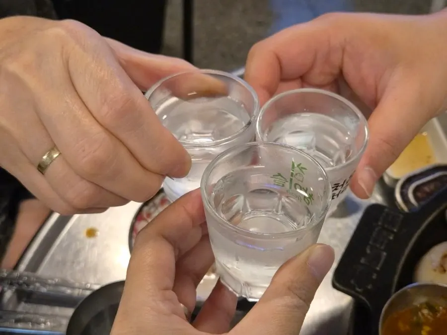 A bottle of soju placed alongside the meat