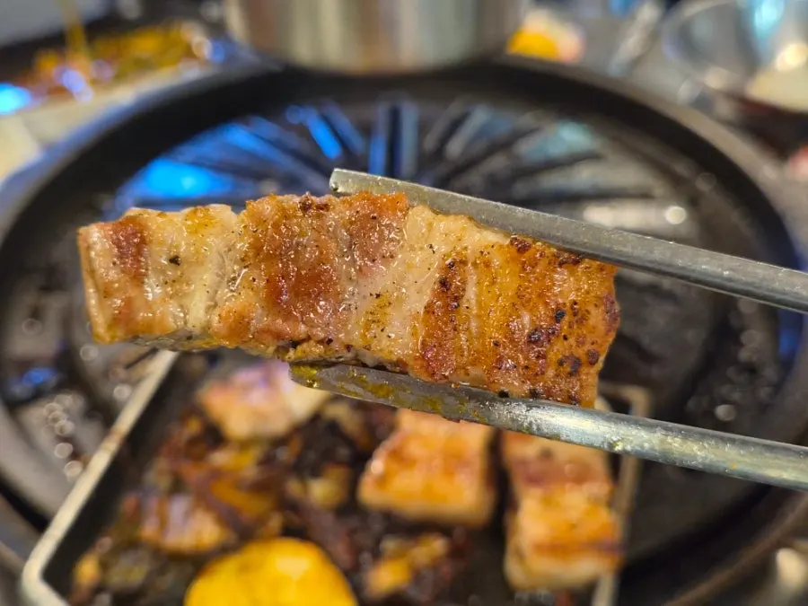 A table of grilled pork belly with ssam vegetables and side dishes