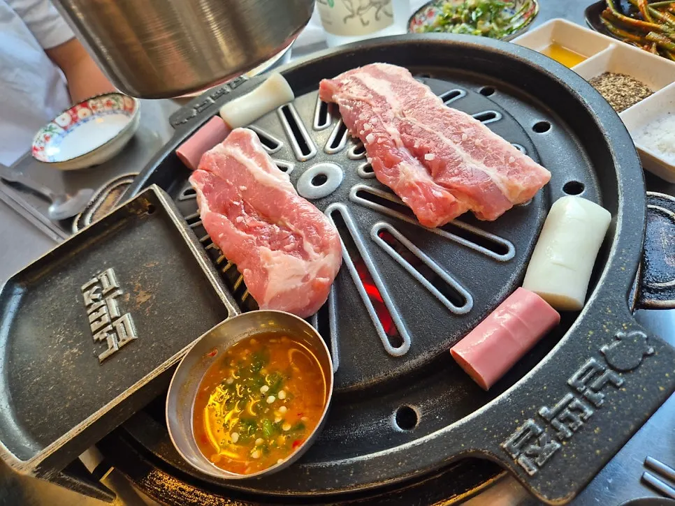 Pork belly grilling on a plate that drains grease downward