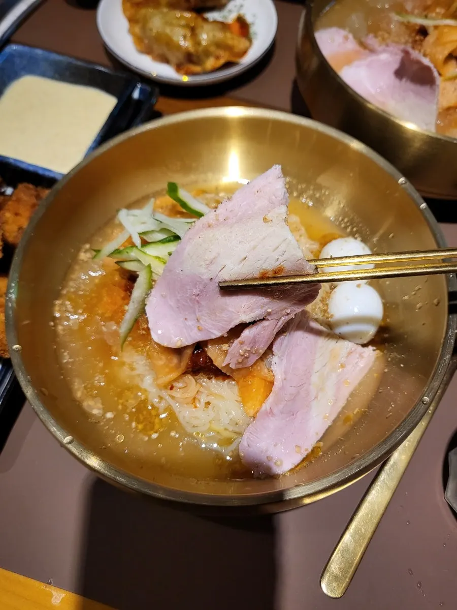 Meat and quail eggs on top of the bibim milmyeon