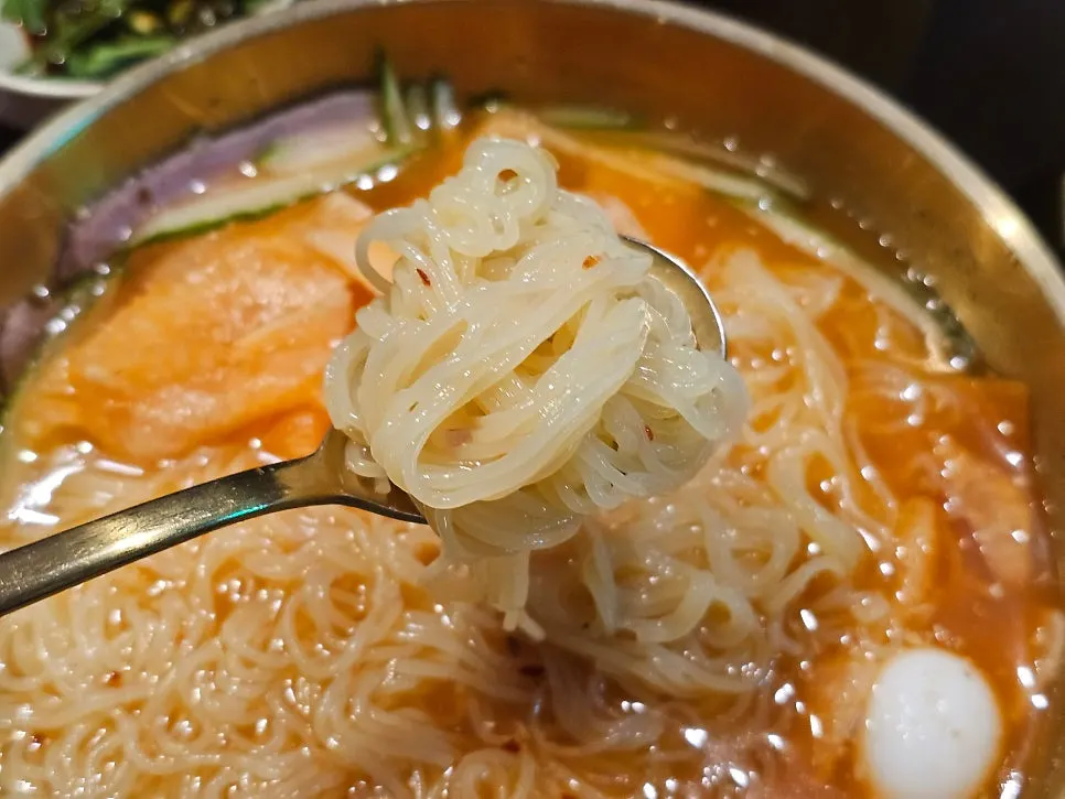 Lifting up a bite of chewy milmyeon noodles