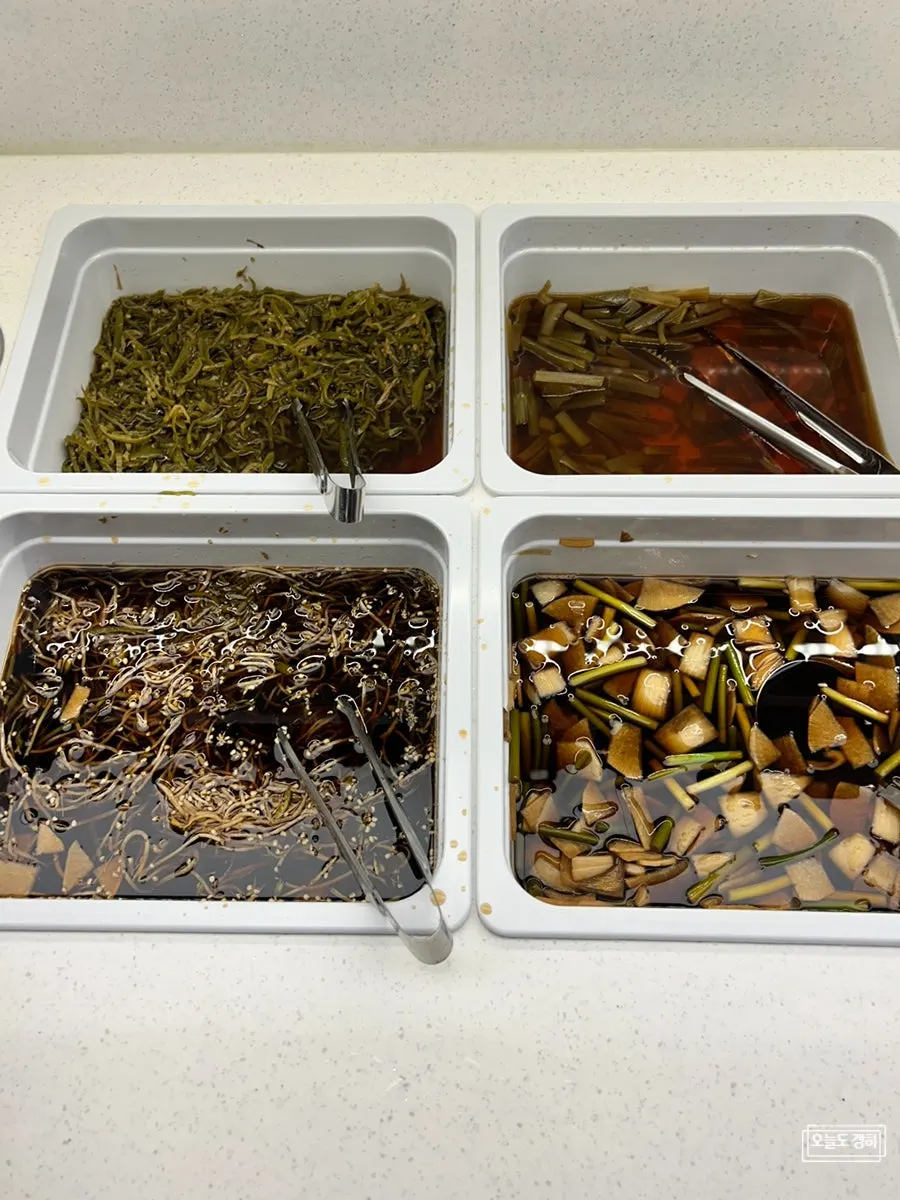 Side dish containers of pickles including chili, mung bean sprout, and gungchae on the self-serve bar