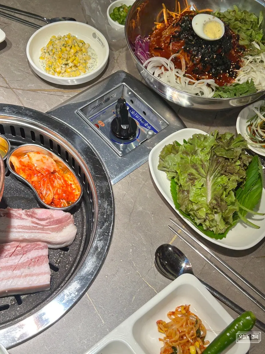 Full table spread with pork belly, jjolmyeon, and soju