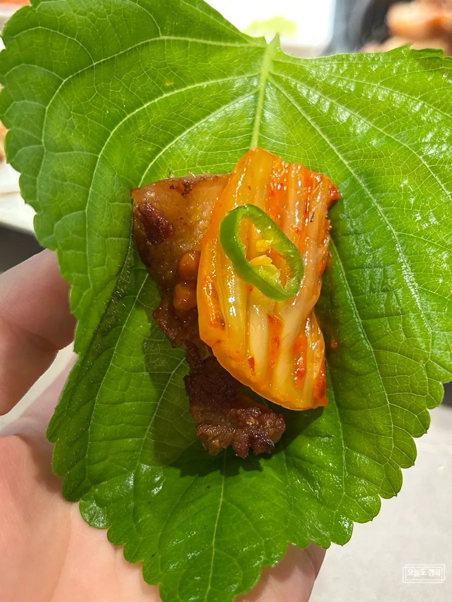 A perilla leaf wrap topped with grilled kimchi