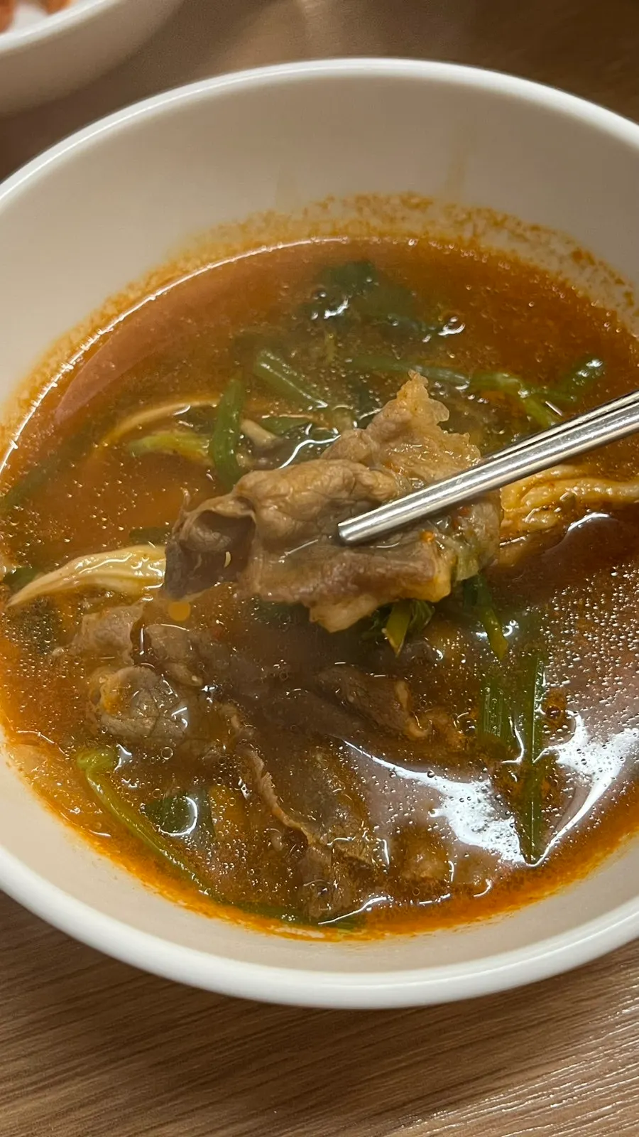 Thin slices of beef being swished in the broth