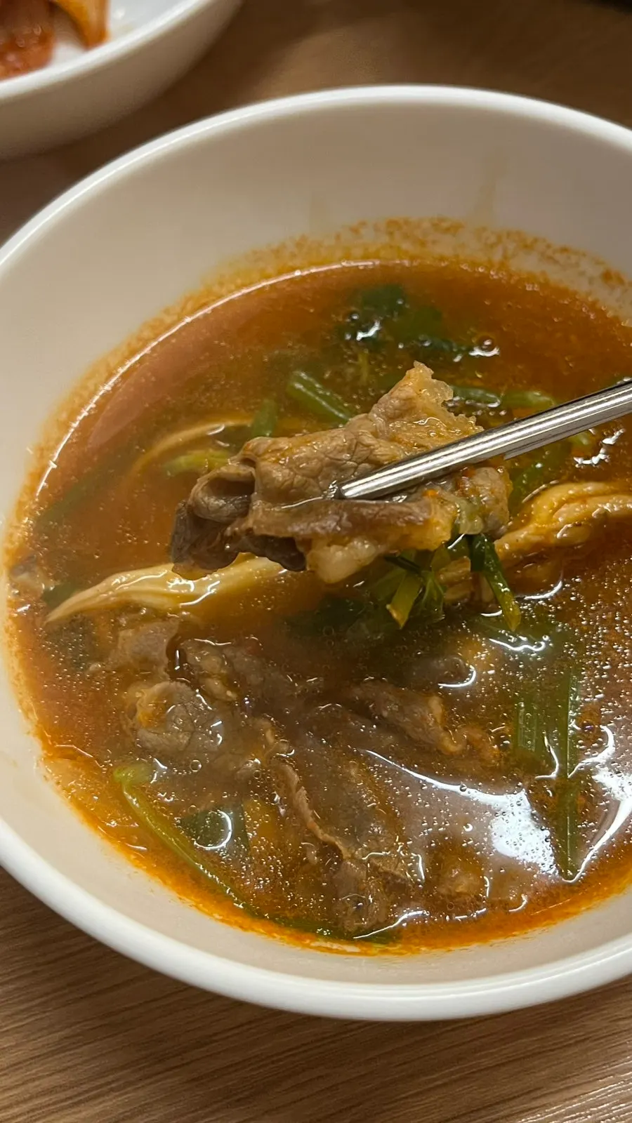 Chopsticks lifting cooked beef out of the pot