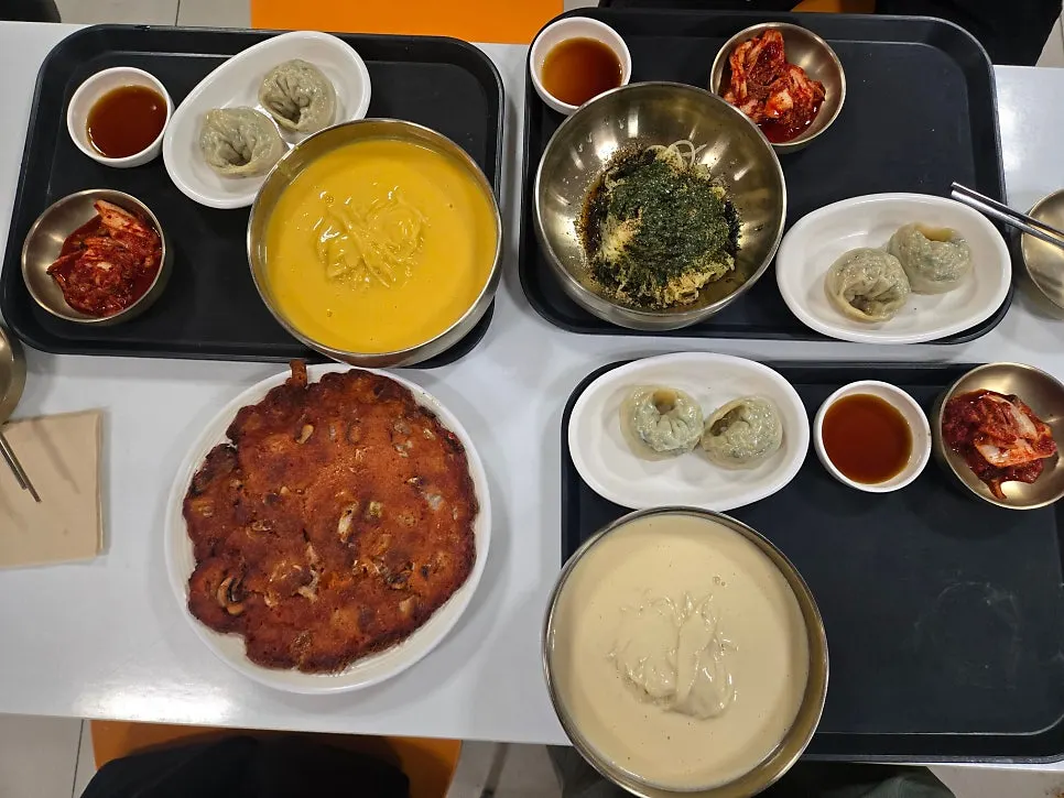 Three bowls of kongguksu and kimchijeon laid out on the table