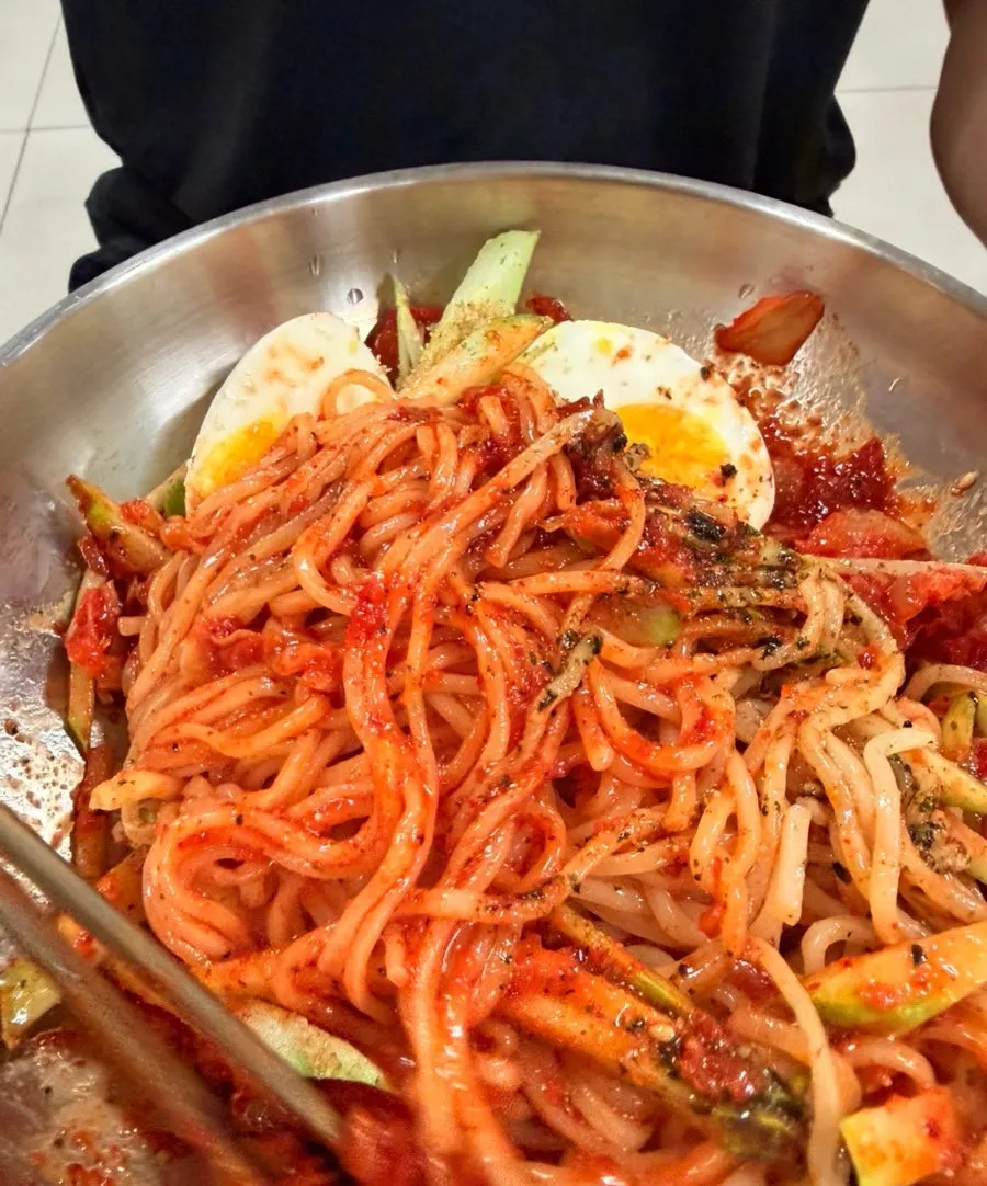 A bite of bibim guksu with the tangy-sweet sauce coating the noodles
