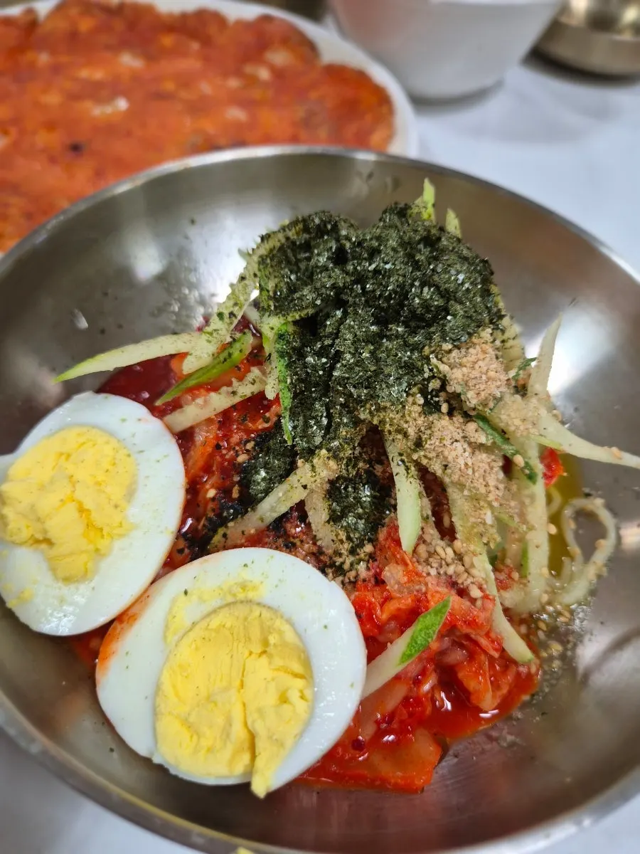 Bibim guksu topped with kimchi, cucumber, and gim flakes