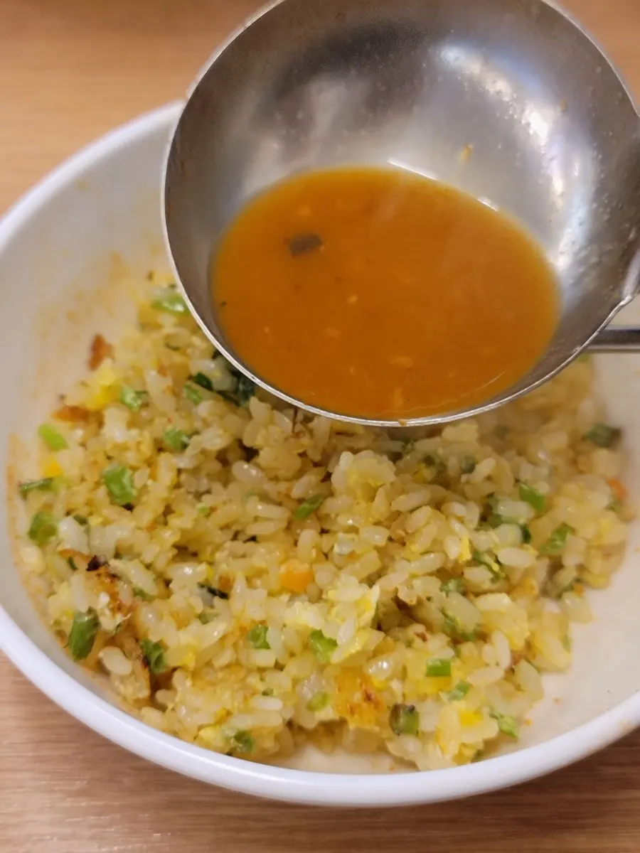 A spoonful of fried rice with added broth