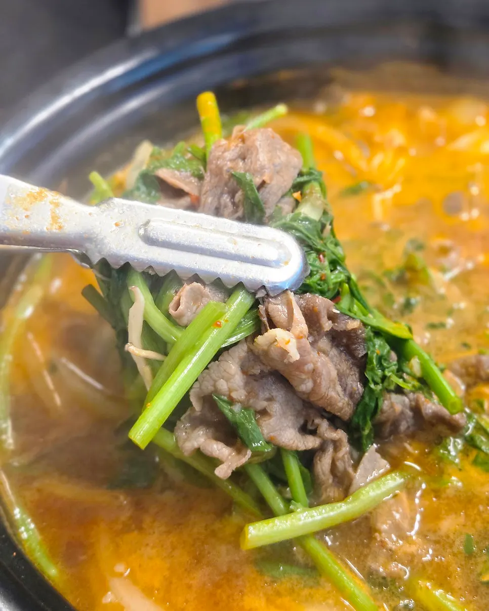 Pot of spicy broth simmering with minari