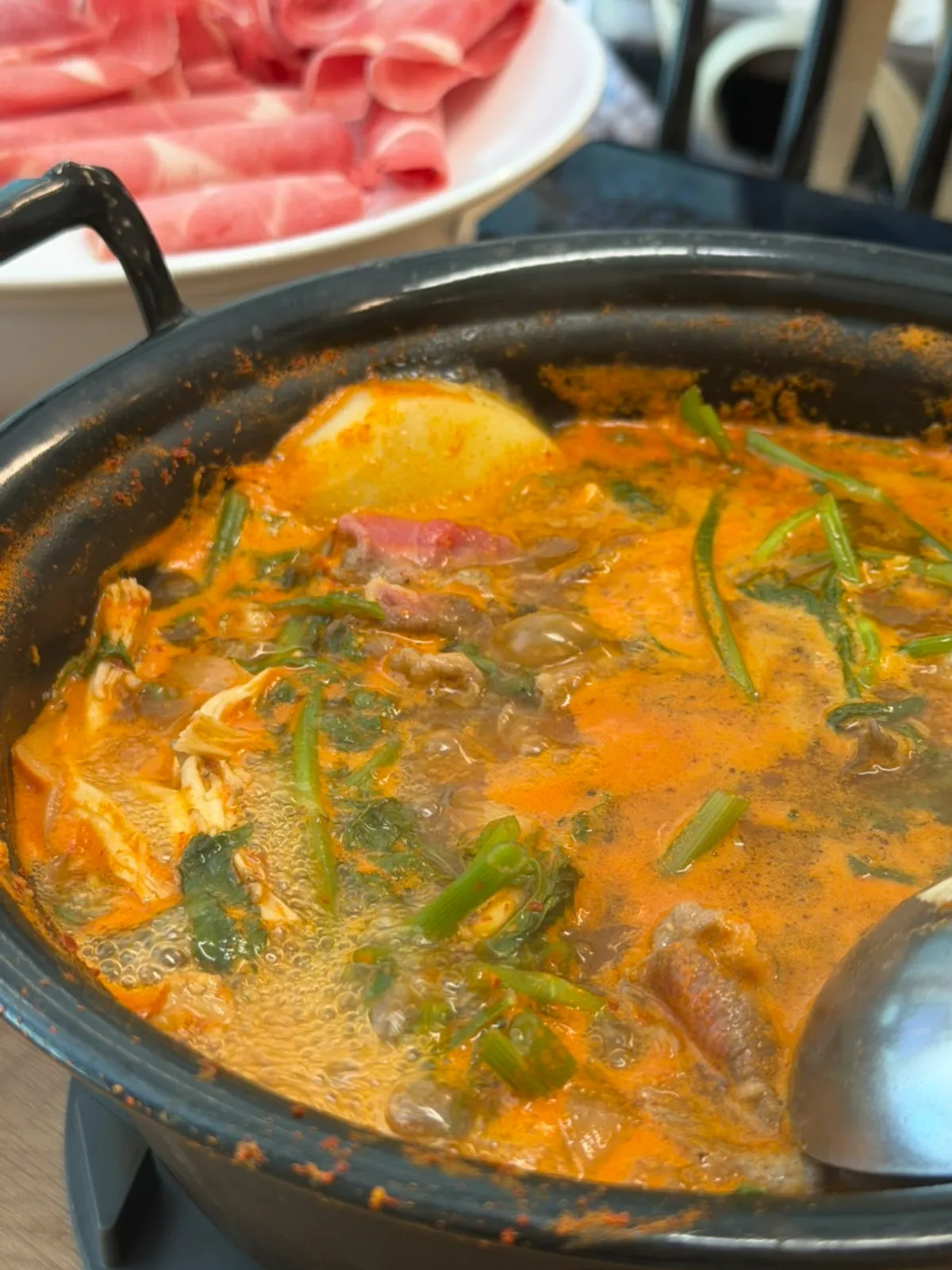 Plate of cooked meat and minari lifted out of the pot