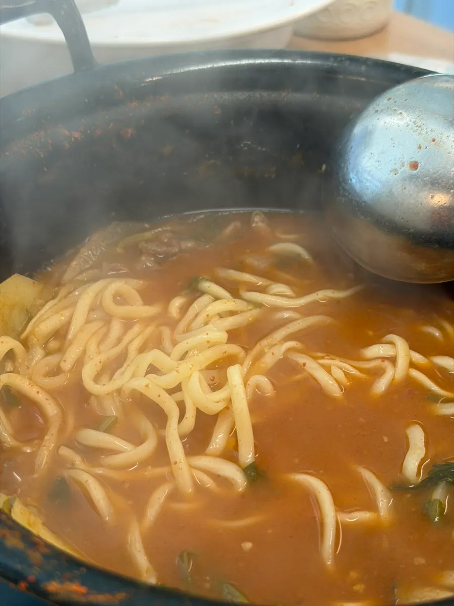 Kalguksu noodles simmering in the red broth