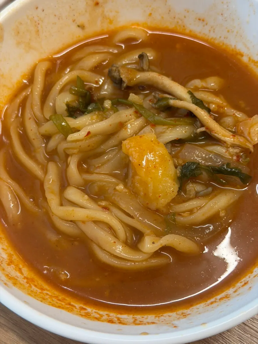 A chopstick-full of kalguksu noodles soaked in the spicy broth