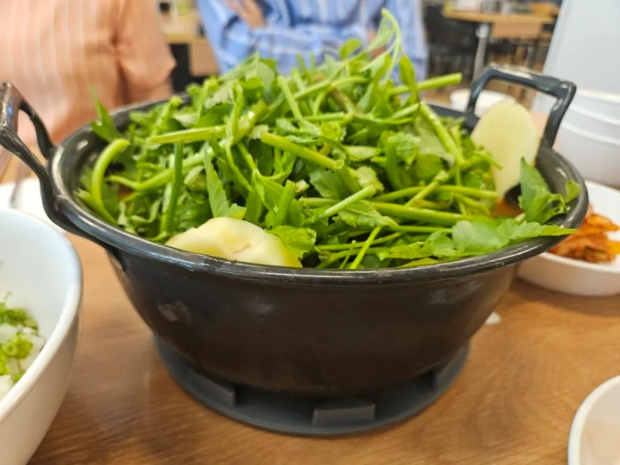 Spicy kalguksu pot piled high with minari