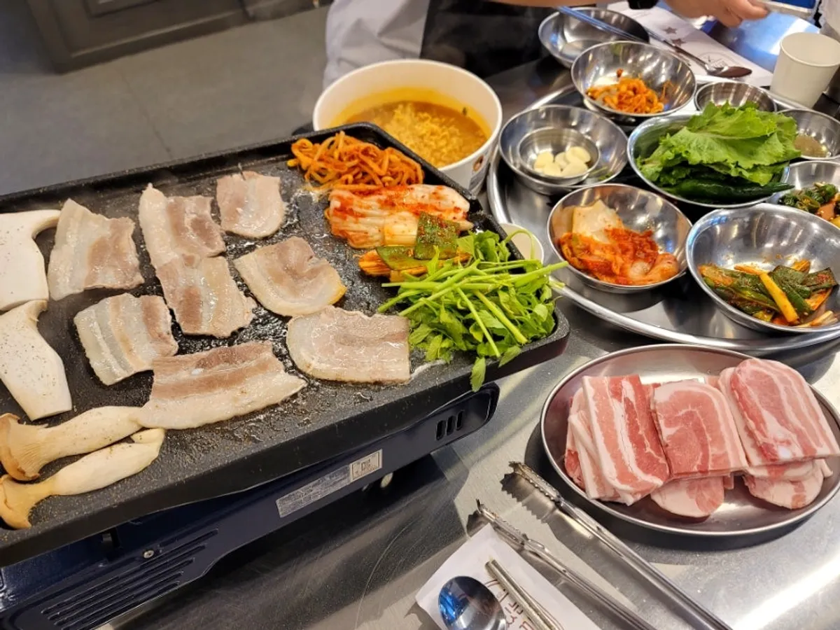 Frozen pork belly, minari, and kimchi on the grill