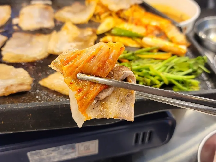A piece of pork belly topped with grilled kimchi