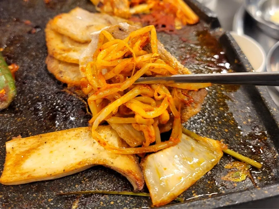 Minari and pork belly cooking on the grill