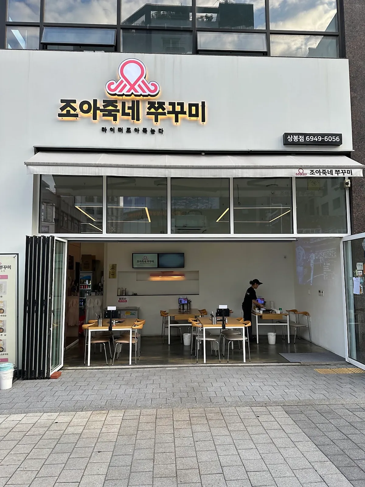 Exterior and outdoor terrace tables of Joajukne Jjukkumi at the entrance of Sangbong Meokja Alley