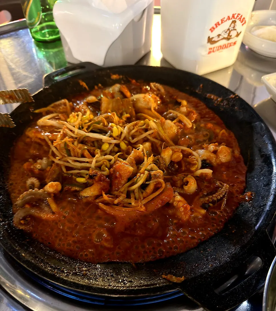 A piece of jjukkumi coated in spicy-sweet sauce