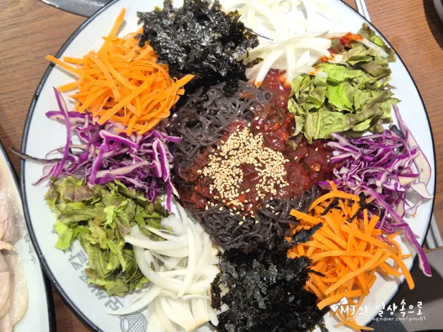 Makguksu topped with vegetables and gim flakes