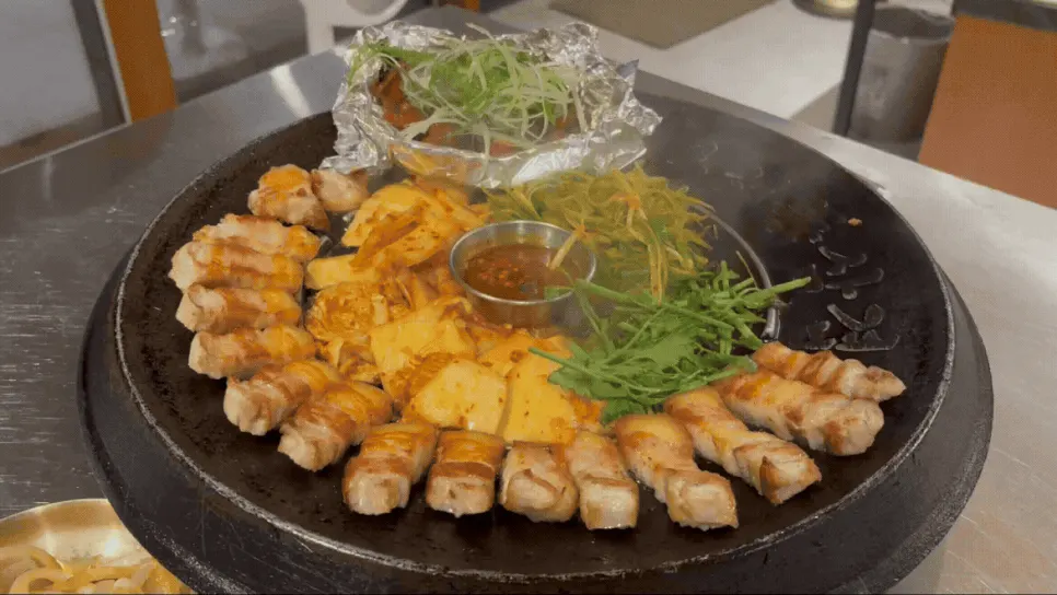 삼겹살과 목살, 김치와 미나리가 담긴 무쇠판