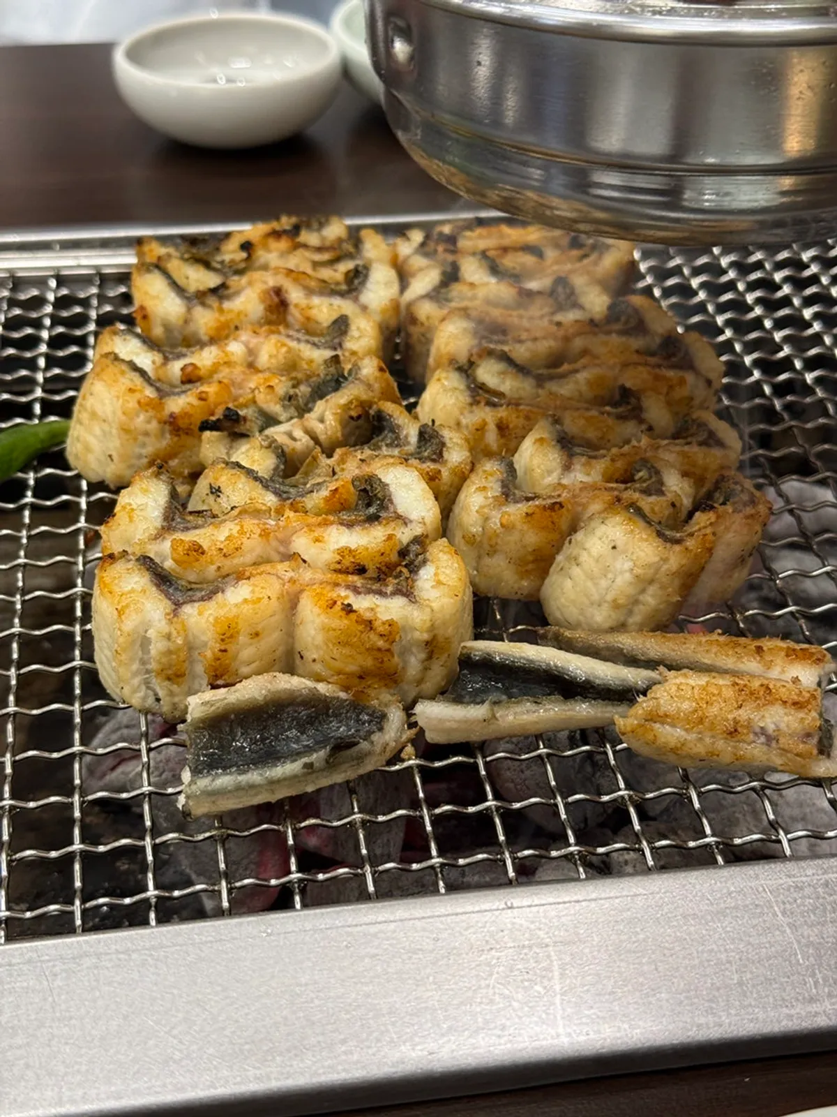 A staff member grilling par-cooked eel
