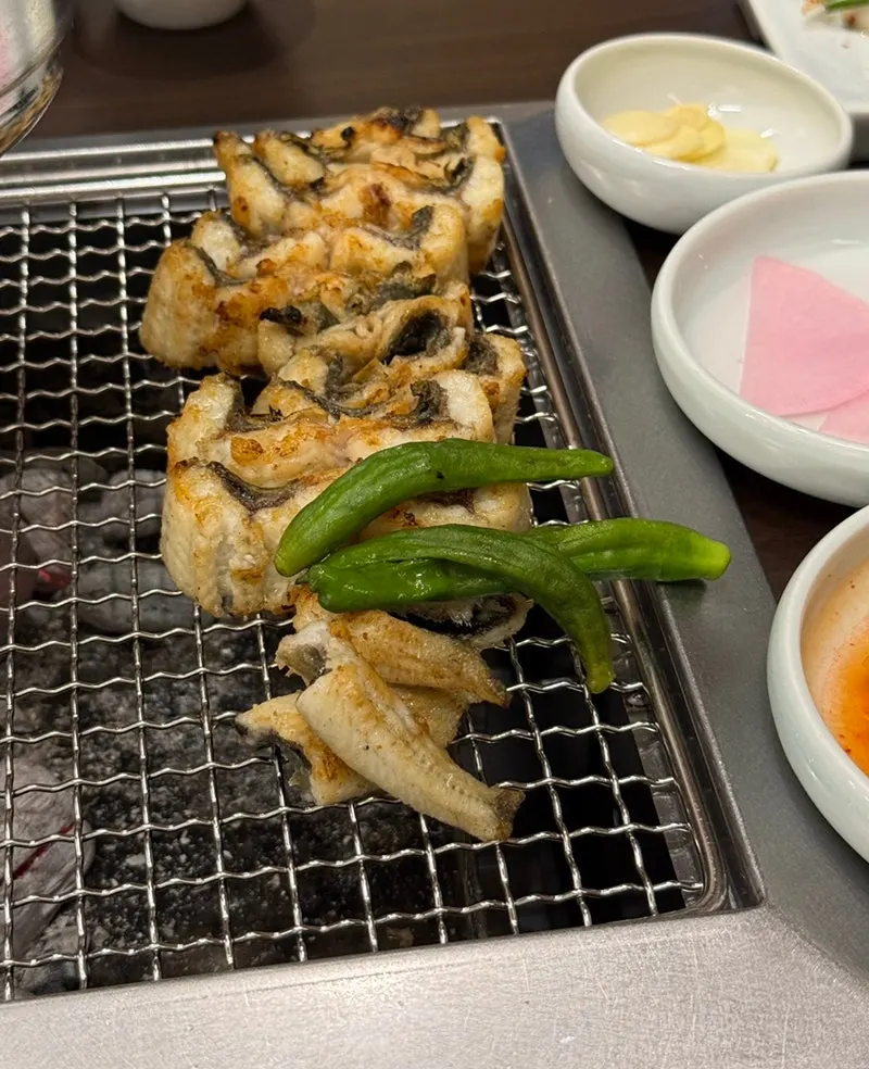 Salt-grilled eel cooking over charcoal