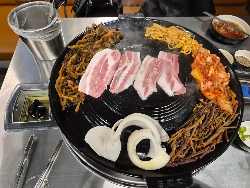 Thin-sliced pork belly and thick pork neck cooking on the cauldron-lid grill